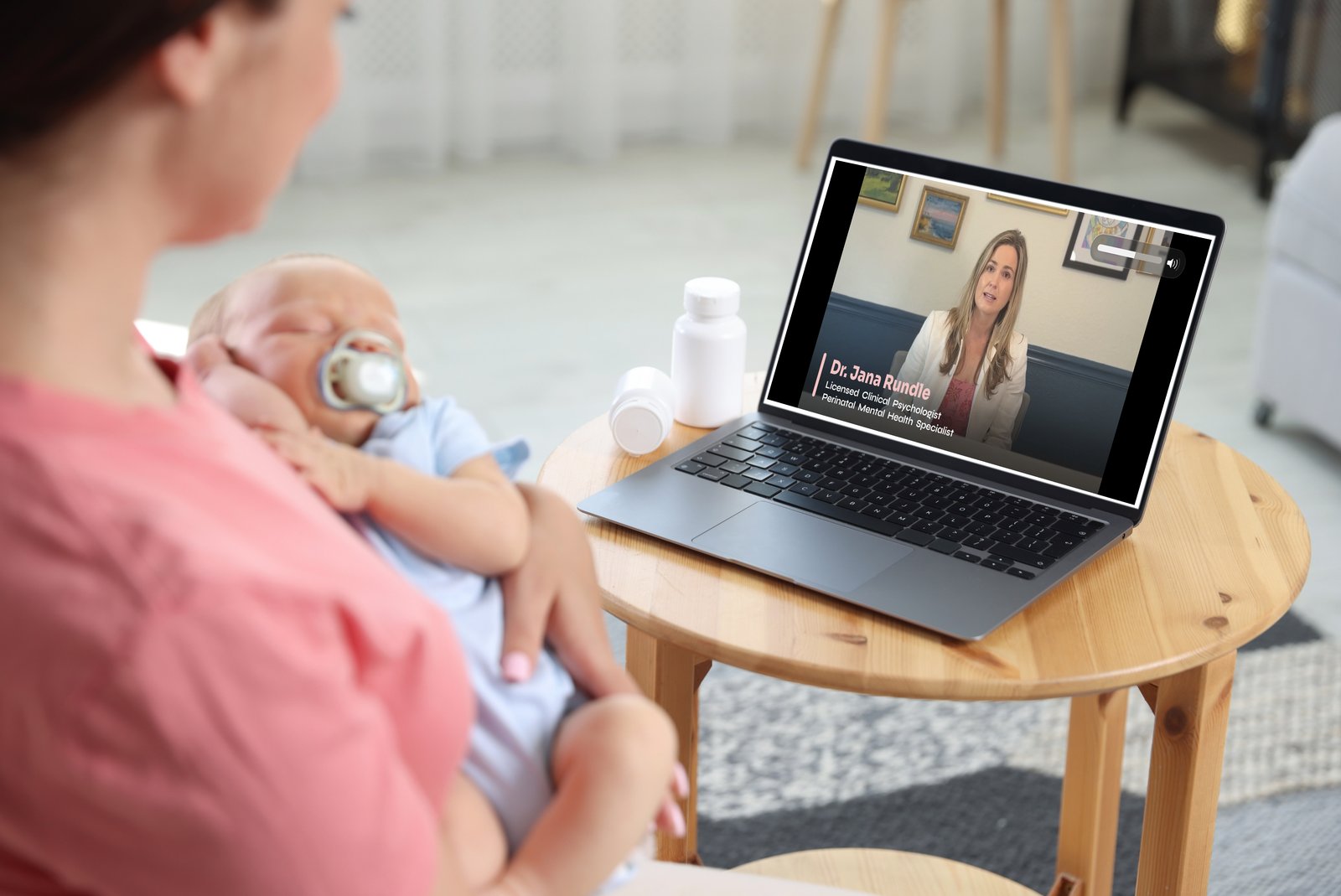 Mom holding baby while watching a video lesson with Dr. Jana Rundle